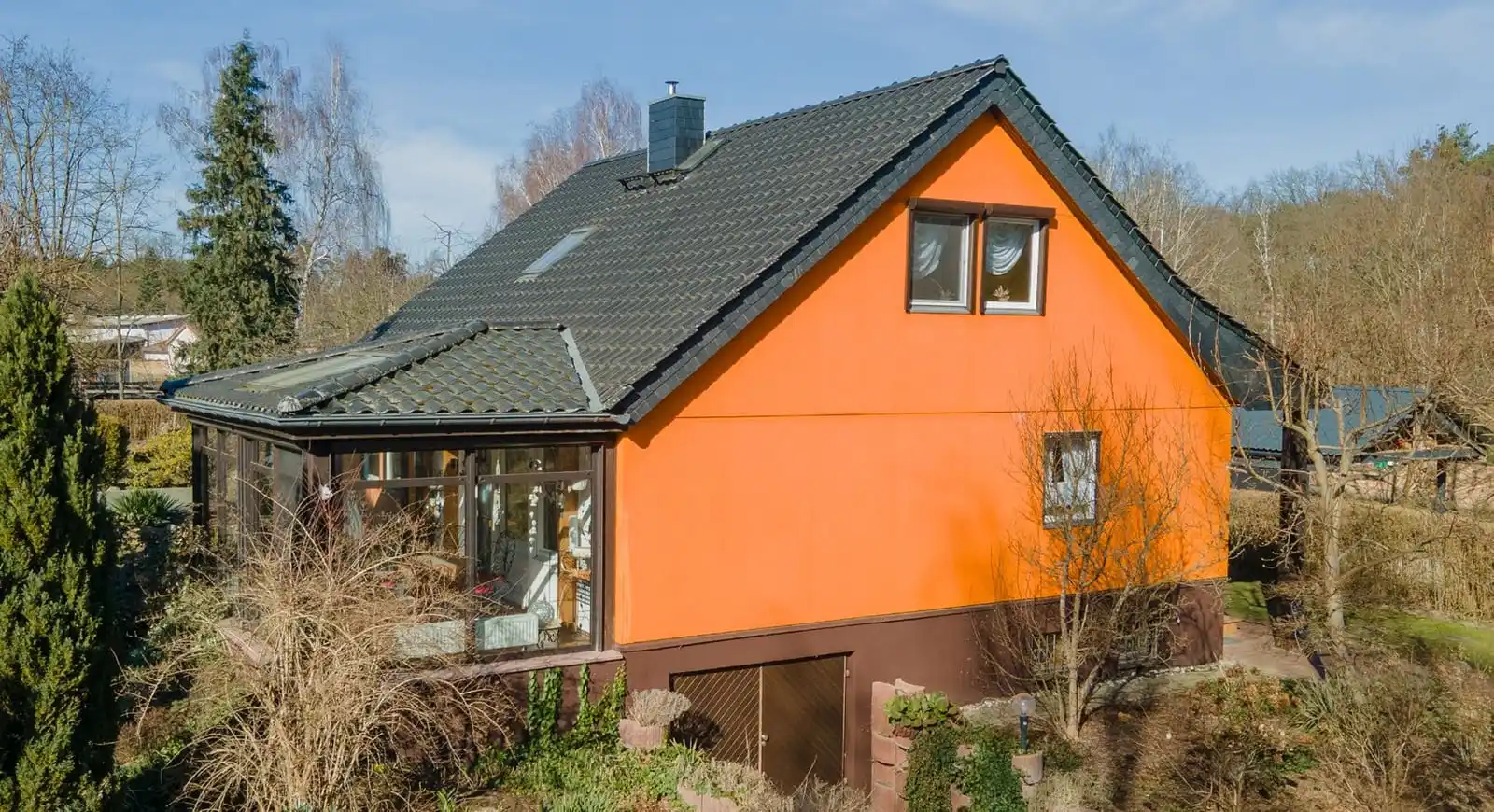 Orangefarbenes Einfamilienhaus mit dunklem Dach und Wintergarten in Beeskow