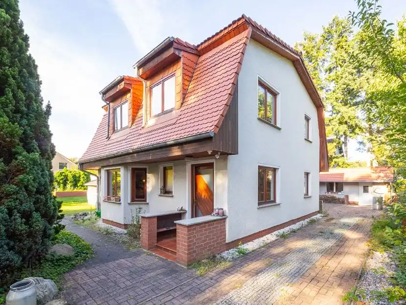Weißes Einfamilienhaus mit rotem Mansarddach und gemauerter Eingangstreppe in Berlin-Müggelheim, Abendsonne