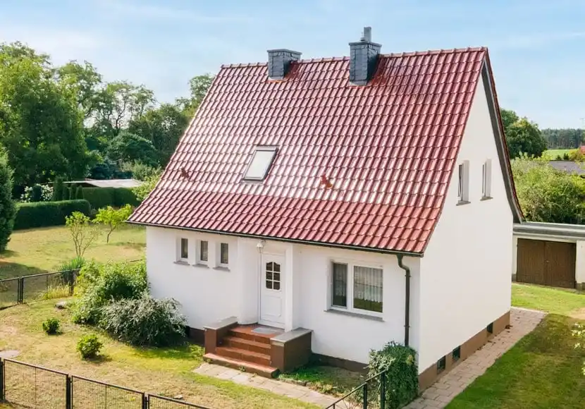 Weißes Wohnhaus mit rotem Ziegeldach und Garten in Weichensdorf bei Friedland
