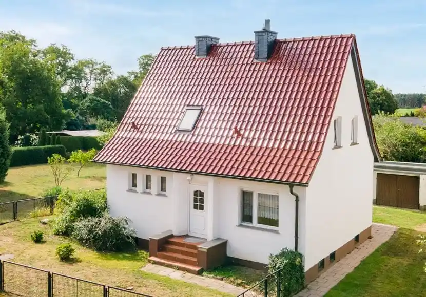 Weißes Wohnhaus mit rotem Ziegeldach und Garten in Weichensdorf bei Friedland