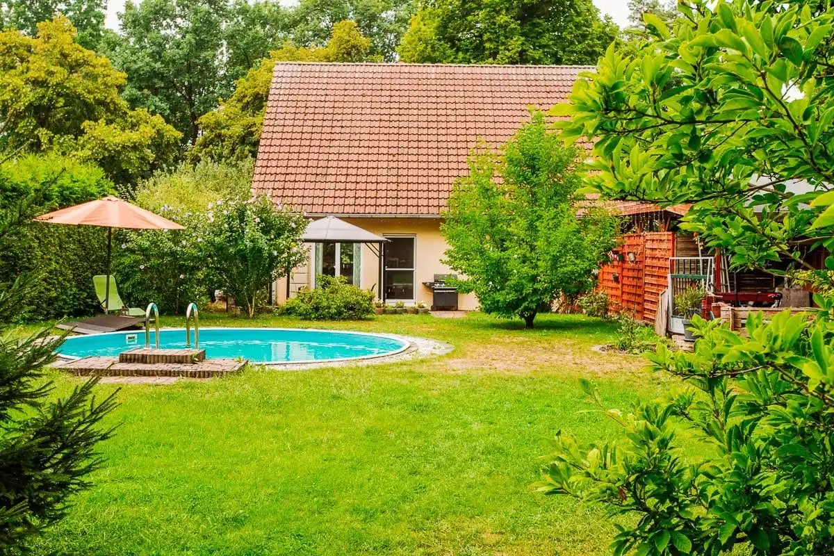 Einfamilienhaus mit Ziegeldach hinter großem Garten mit rundem Pool in Hangelsberg bei Grünheide