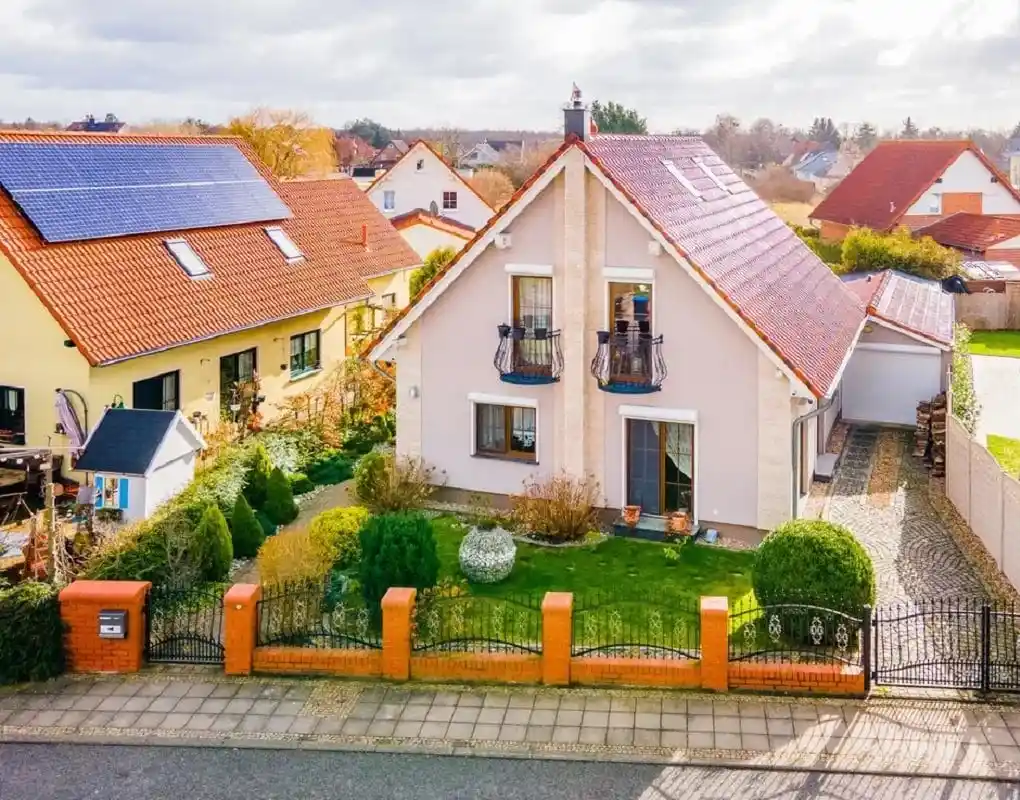 Einfamilienhaus mit Ziergiebel, zwei Balkonen und Vorgarten mit Klinkerzaun in Brieselang, von oben fotografiert