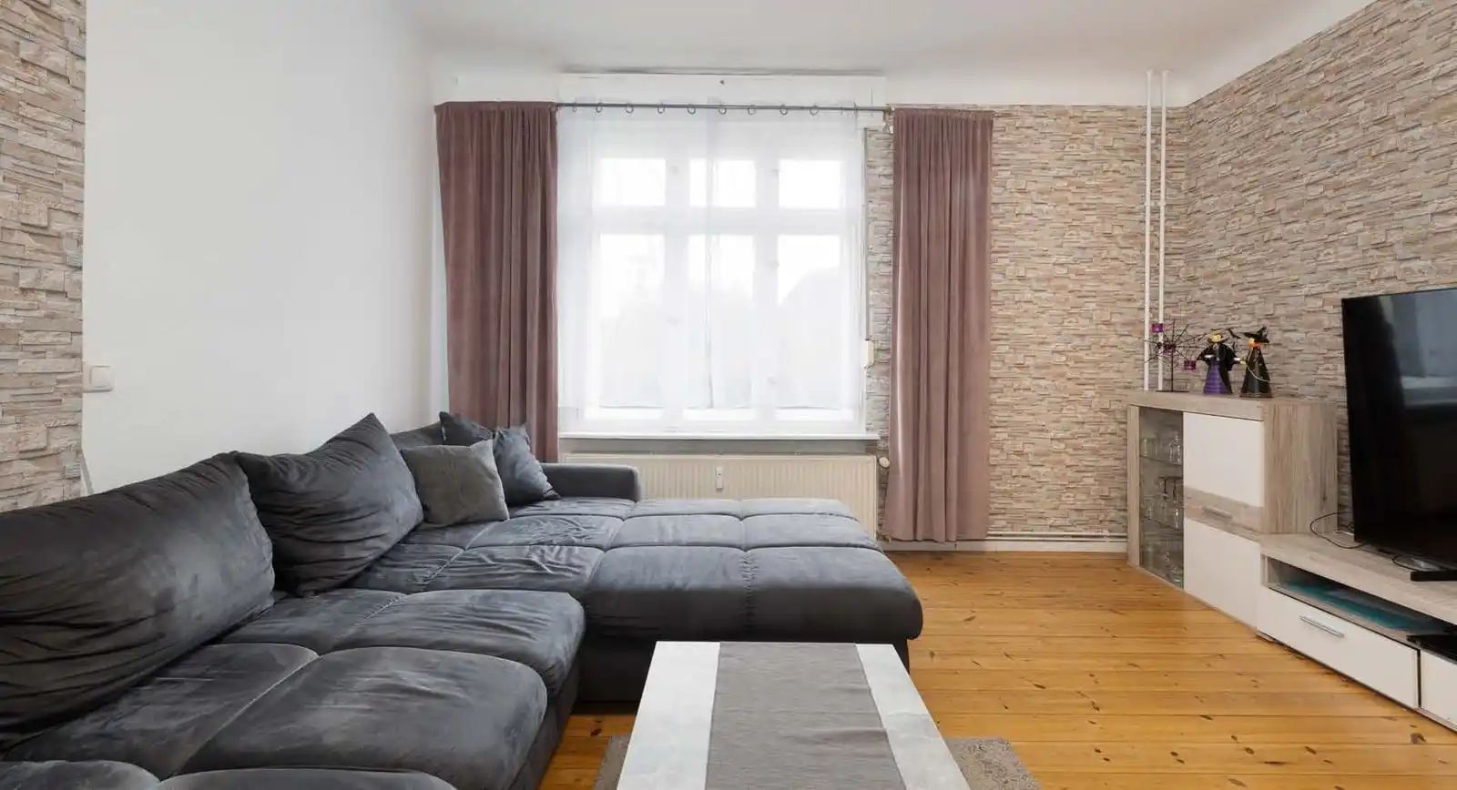 Wohnzimmer mit Ecksofa und Dielenboden in der Eigentumswohnung in Hennigsdorf