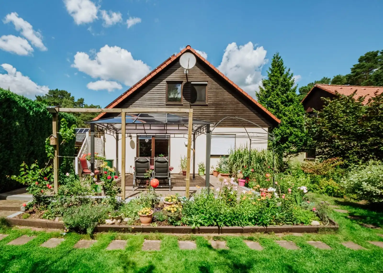 Giebelseite des Einfamilienhauses mit Terrasse und Gartenbeeten in Borkheide