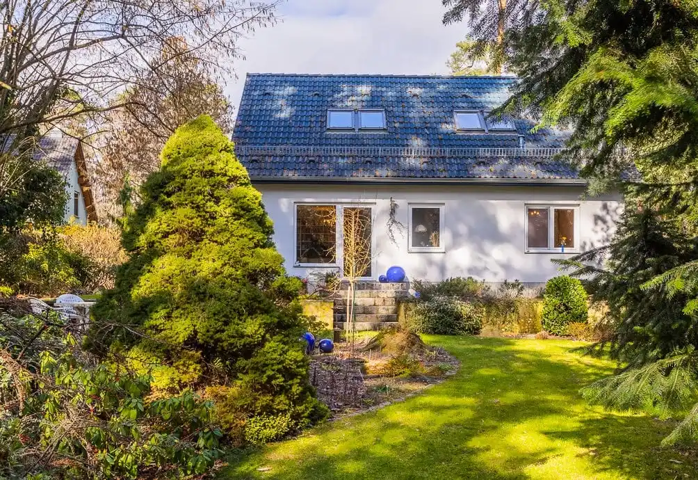 Gartenseite des Einfamilienhauses mit Nadelbäumen in Wandlitz