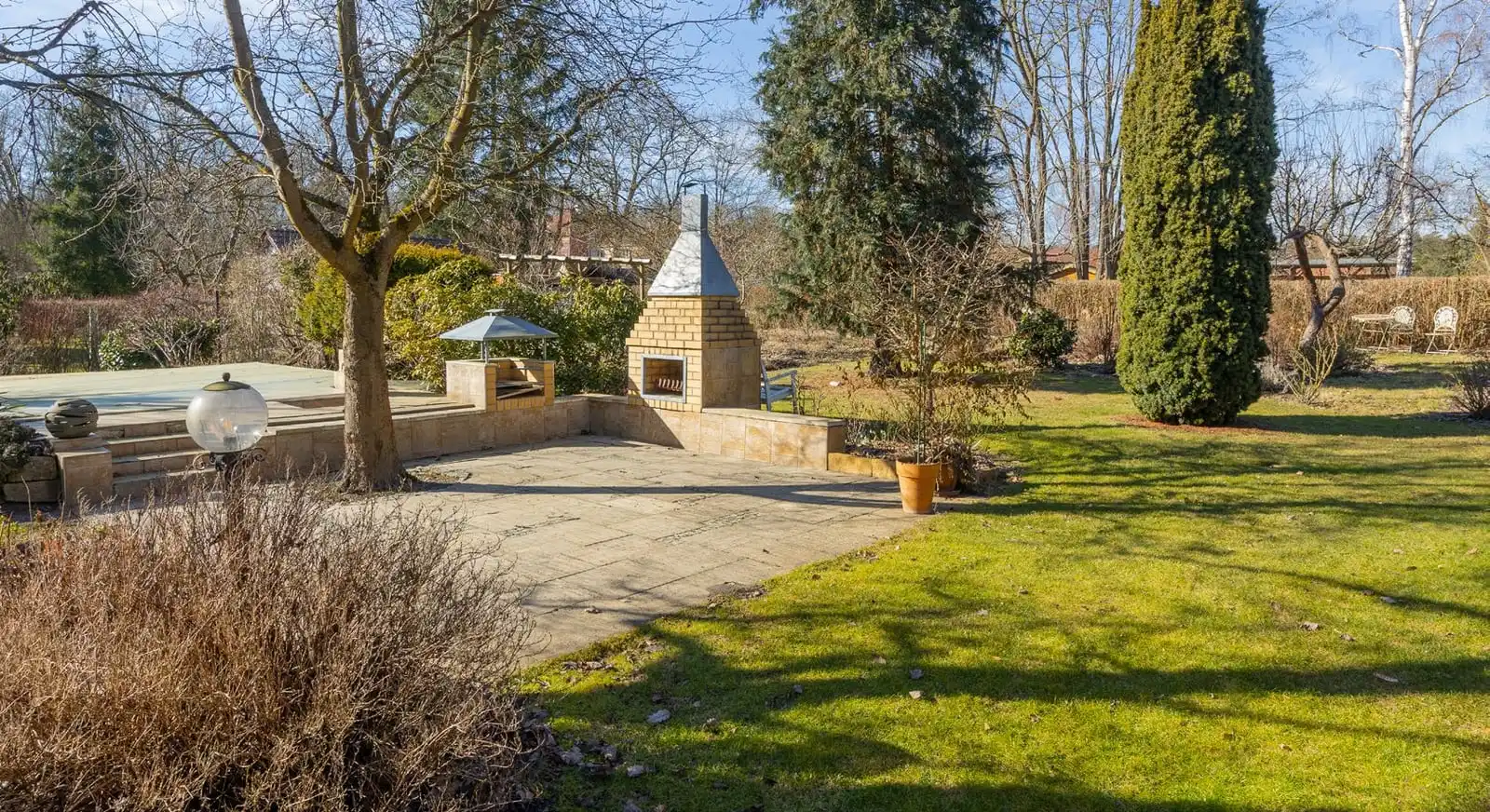 Terrasse mit Grillkamin und Rasen auf dem Grundstück des Einfamilienhauses in Beeskow