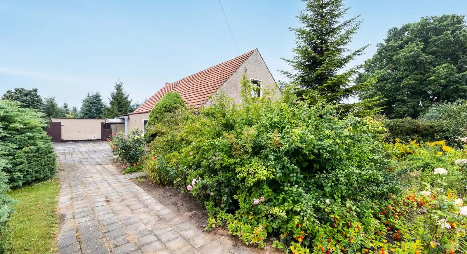 Gepflasterte Einfahrt mit Garten und Garagen am Einfamilienhaus in Neuhof bei Angermünde
