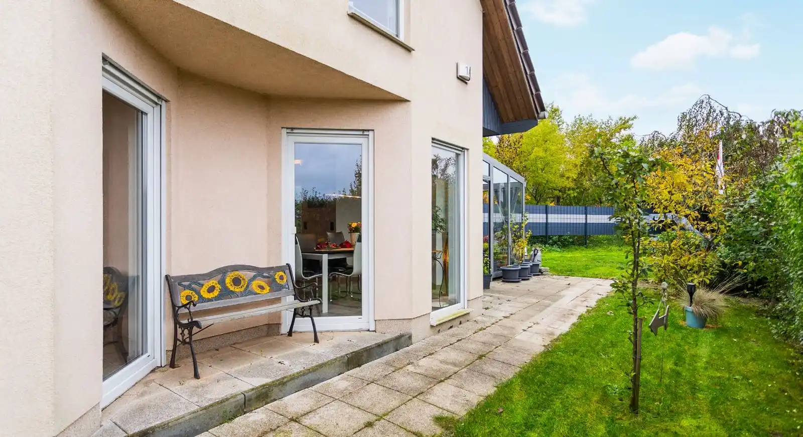 Hausecke mit Fenstertüren, Gartenbank und Rasen am Einfamilienhaus in Ahrensfelde