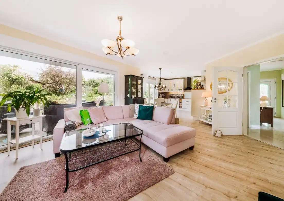 Wohnbereich mit Sofa, Esstisch und Fensterfront im Bungalow in Rauen bei Fürstenwalde