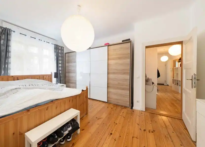 Schlafzimmer mit Holzbett und Schiebetürschrank in der Eigentumswohnung in Hennigsdorf