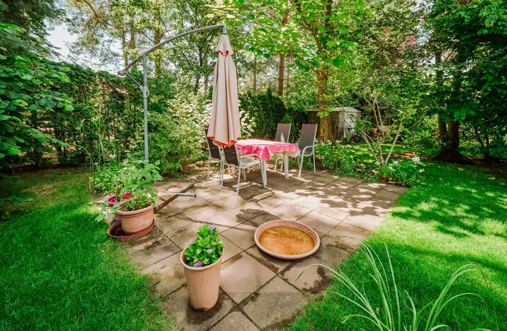 Gartenterrasse mit Sonnenschirm unter Bäumen in Borkheide