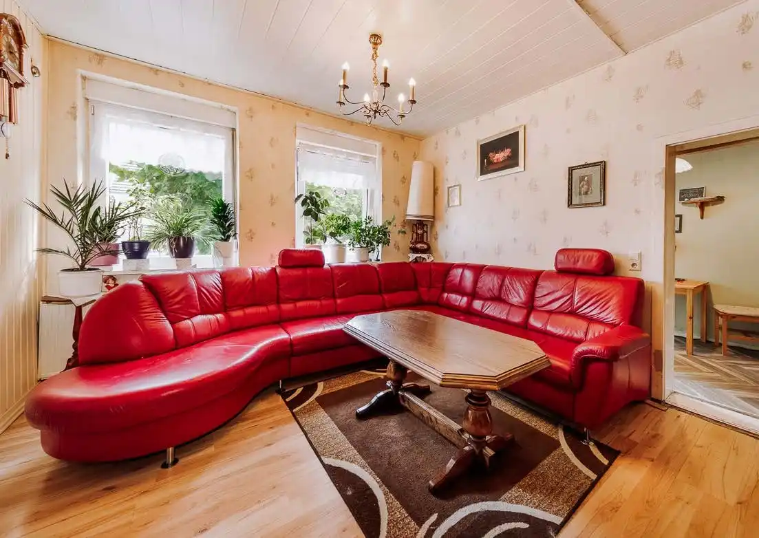 Wohnzimmer mit rotem Ecksofa im Wohnhaus des Dreiseitenhofs in Breddin