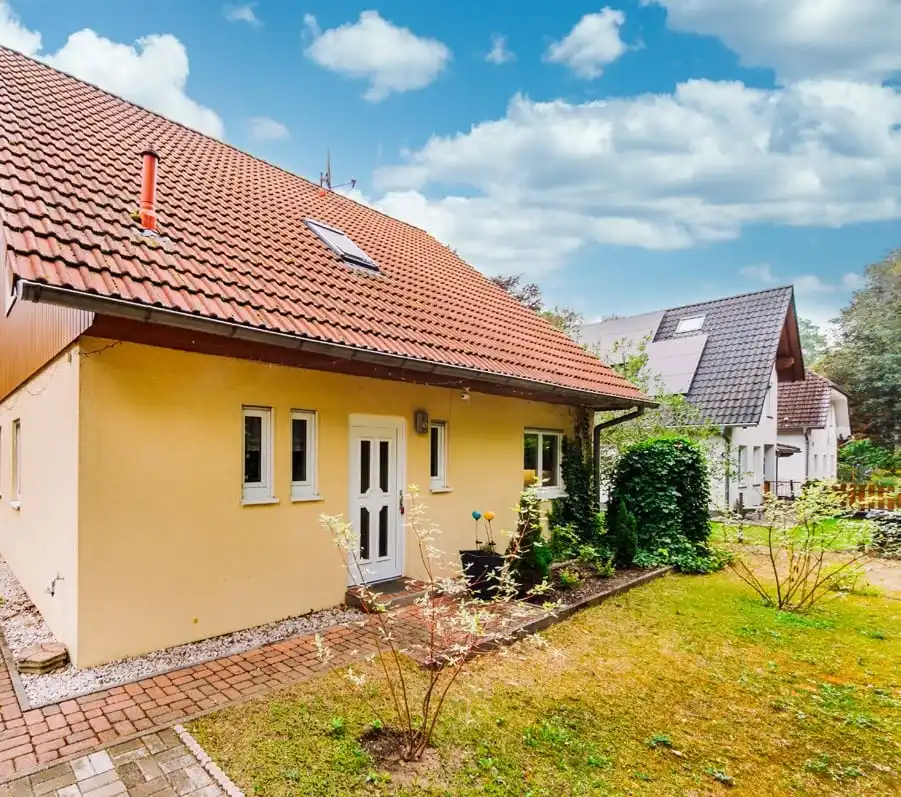 Gelbes Einfamilienhaus mit Eingang und Rasen in Hangelsberg bei Grünheide