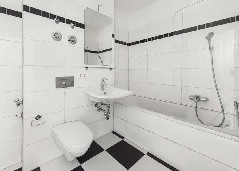 Badezimmer mit Badewanne und schwarz-weißen Fliesen in der Eigentumswohnung in Berlin-Karlshorst