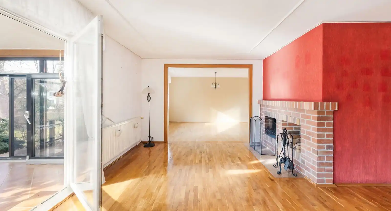 Wohnbereich mit Parkett, Kamin und roter Wand im Einfamilienhaus in Beeskow