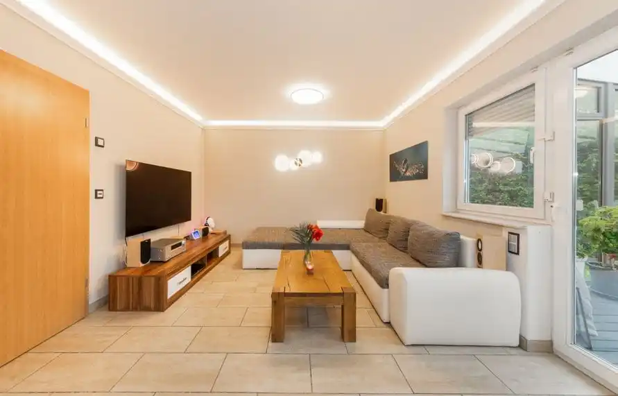 Wohnzimmer mit Lichtband an der Decke, Sofa und Fernseher im Einfamilienhaus in Ahrensfelde