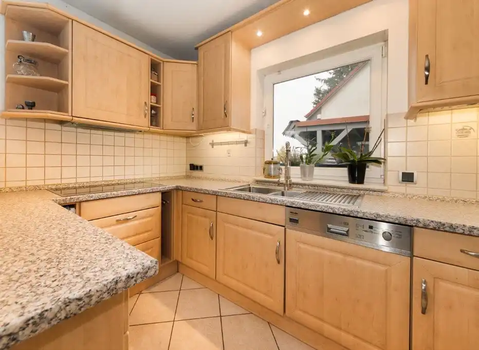Küche mit Holzfronten und Granit-Arbeitsplatte im Einfamilienhaus in Ahrensfelde