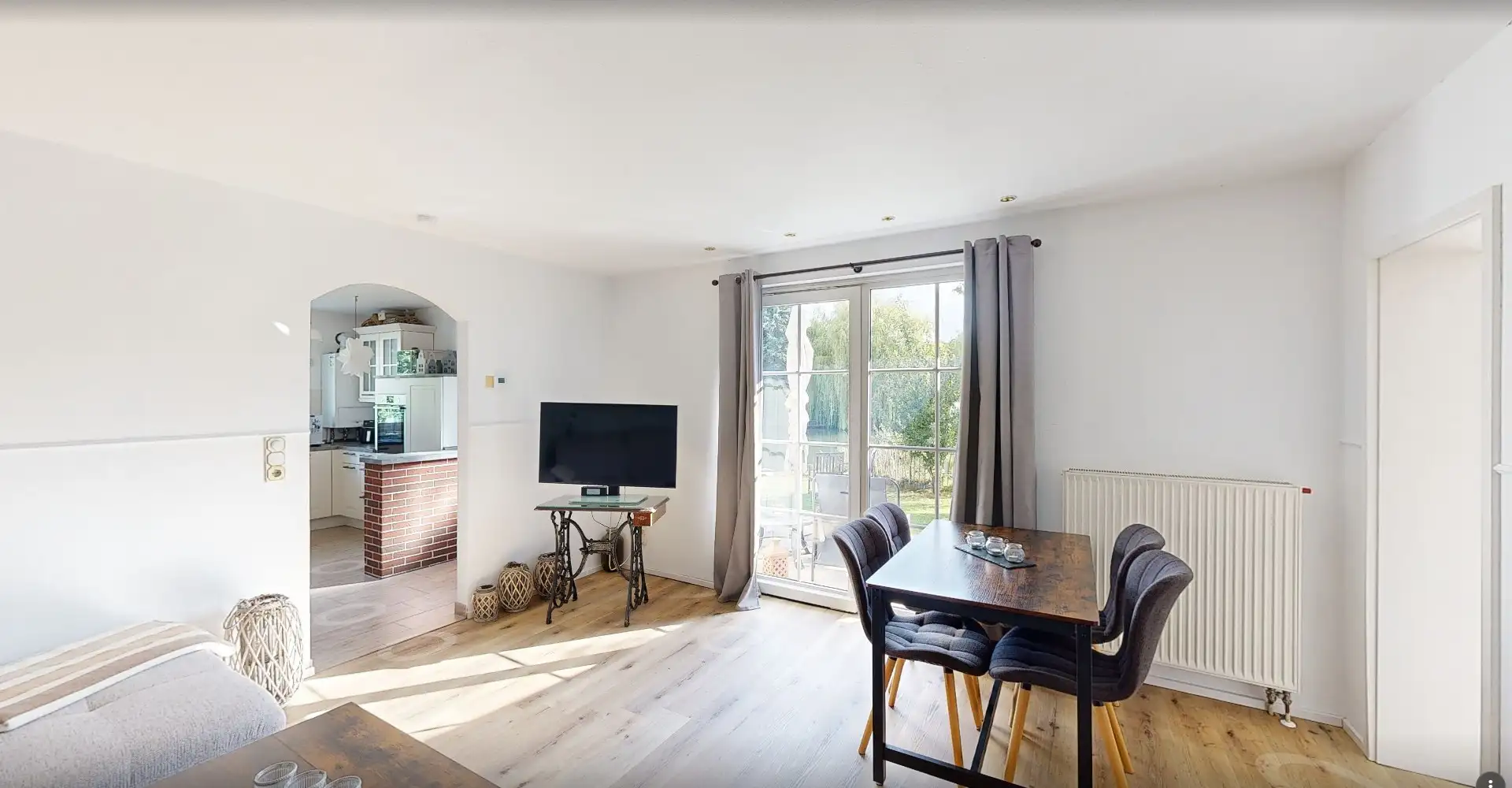 Bildschirmfoto aus dem 360-Grad-Rundgang: heller Wohnraum mit Essplatz und Terrassentür im Bungalow in Rüdersdorf bei Berlin